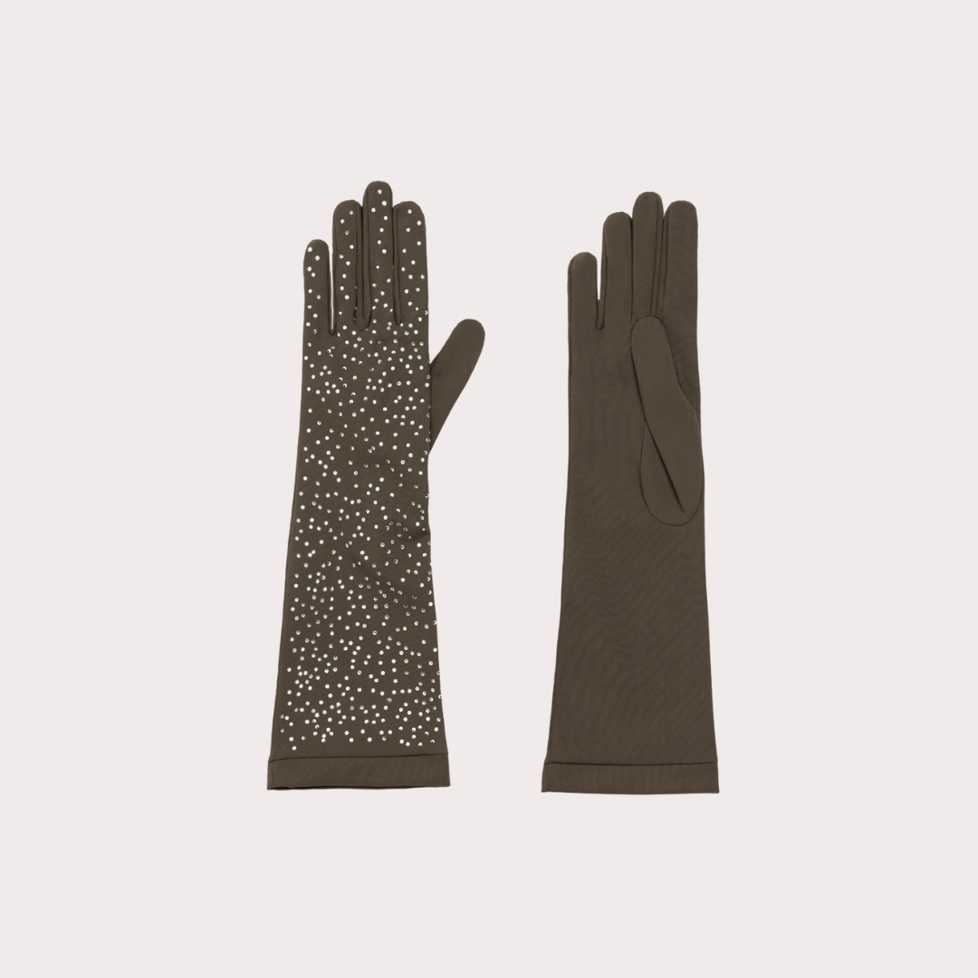 Flat lay of a pair of olive green opera gloves, one embellished with scattered crystals and the other plain, displayed on a light pink background.