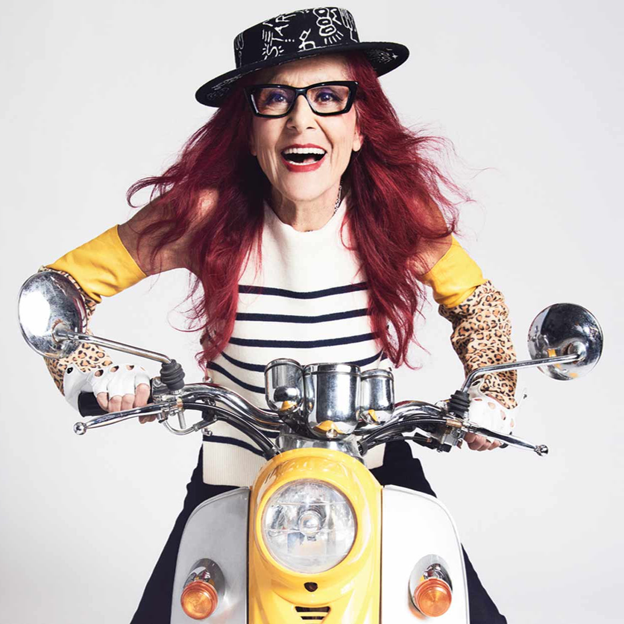 Retro fashion portrait with striped top, yellow sleeves, and vintage scooter