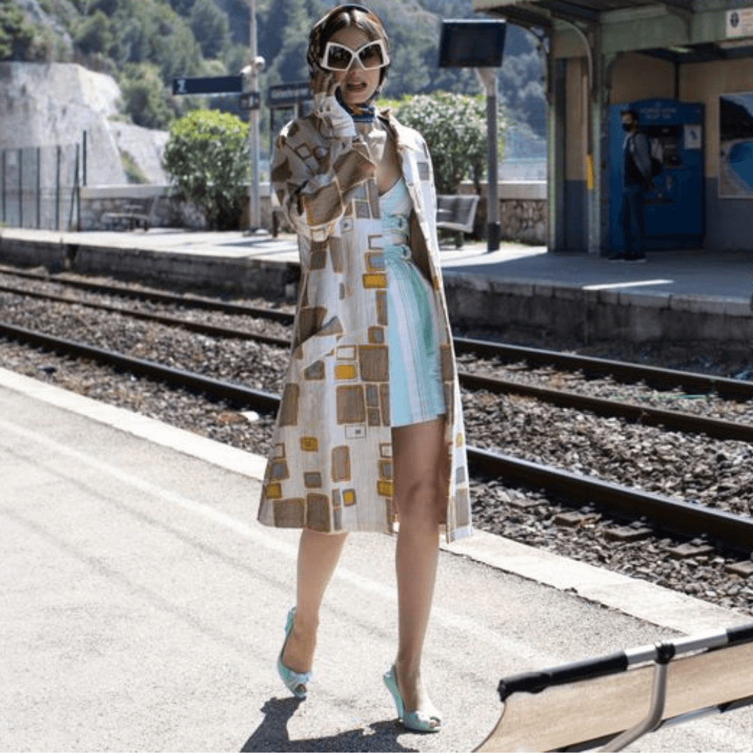 Lilly Collins Wearing virgin white Italian leather fingerless driving gloves with snap closure in Emily in Paris Train Station Scene, designed by Patricia Field