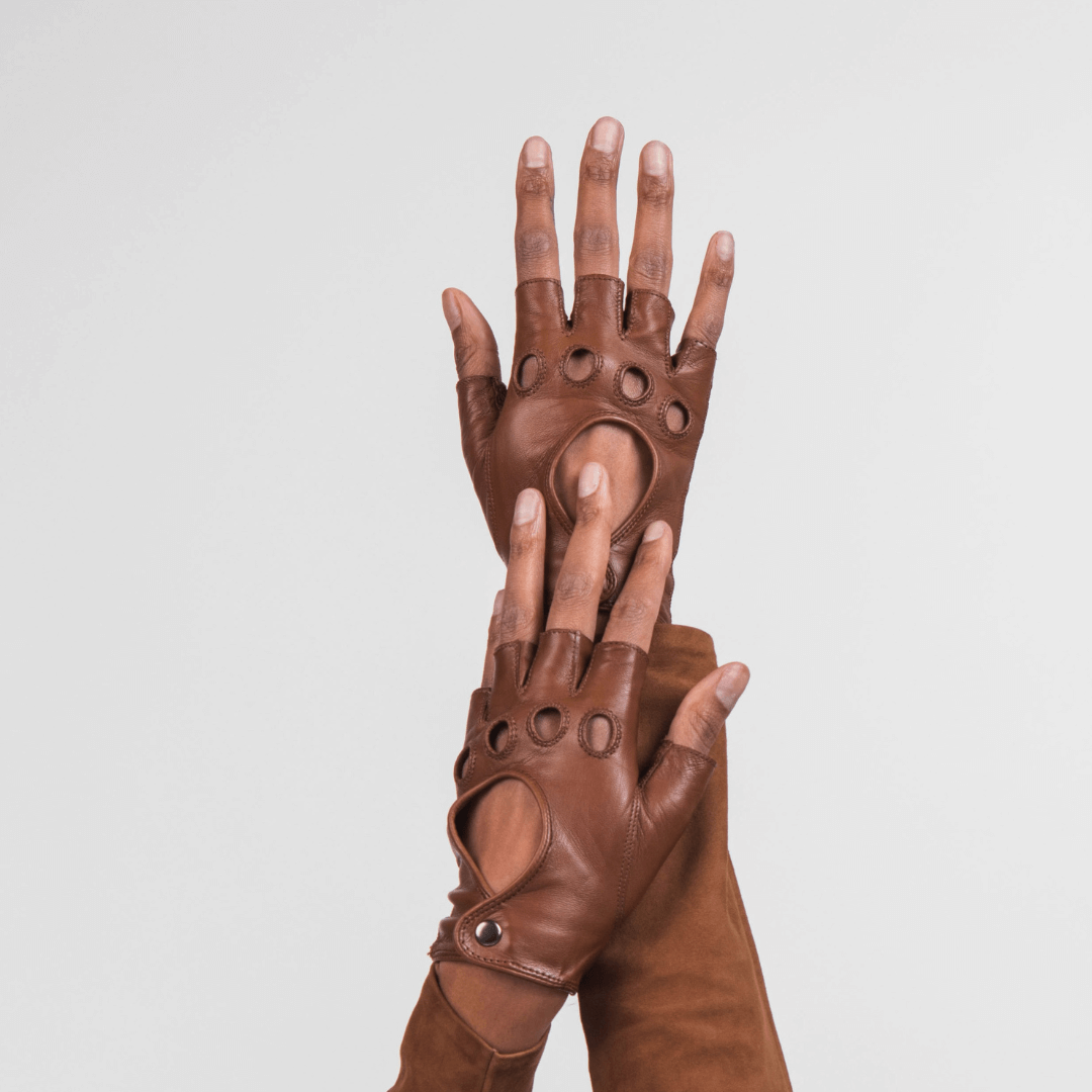 Hand modeling Patricia Field's Horse Saddle Brown Italian leather fingerless driving gloves from Emily in Paris with snap button closure.
