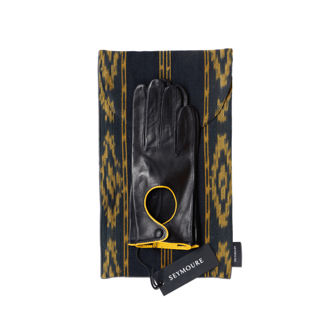 Black leather glove with yellow toggle detail on ikat print background