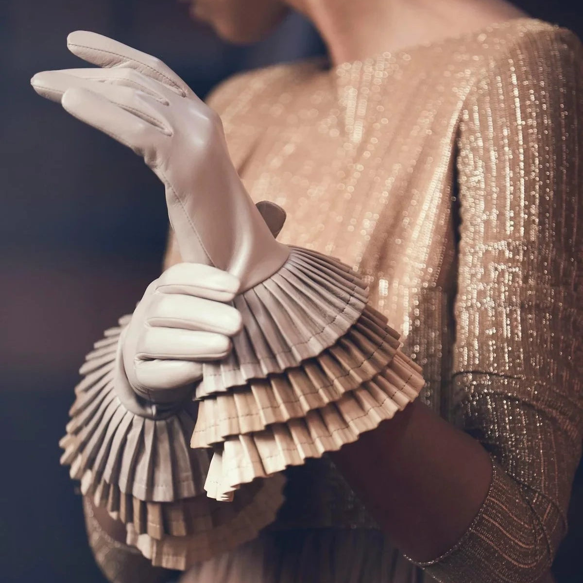 model wearing White leather gloves with dramatic pleated ruffles, haute couture detail gold dress