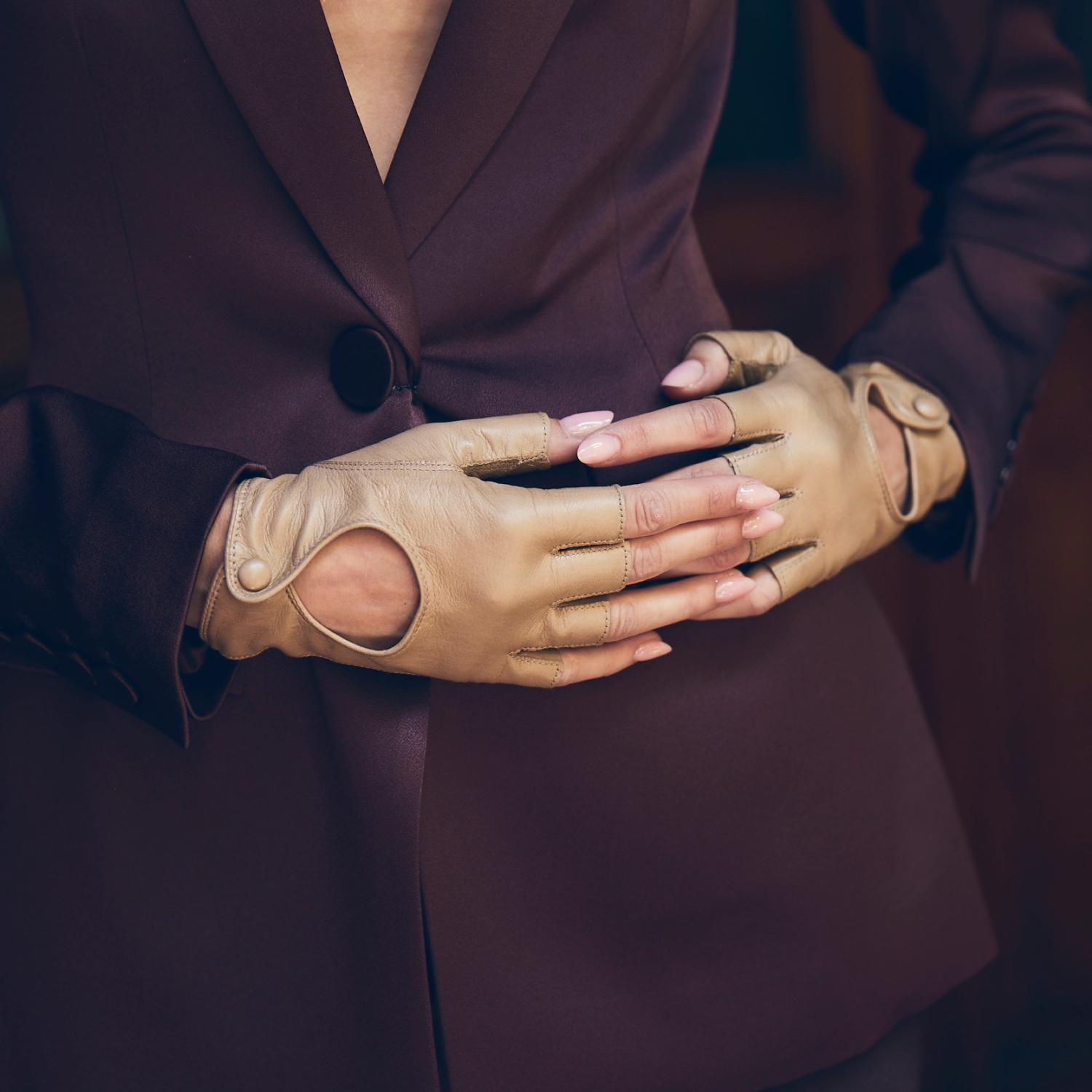 woman wearing nude fingerless gloves on hip intertwined on Burgundy wine color jacket